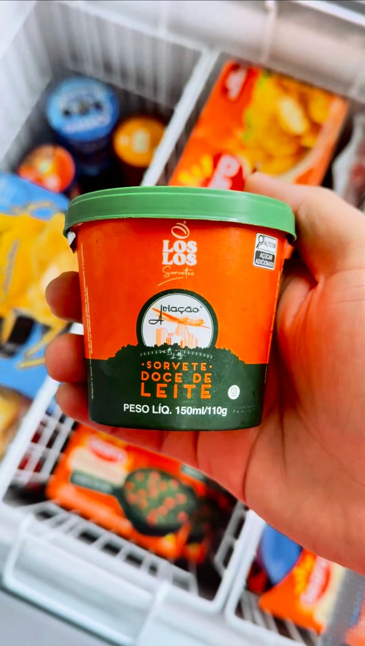 Mão retira um pote de sorvete do freezer